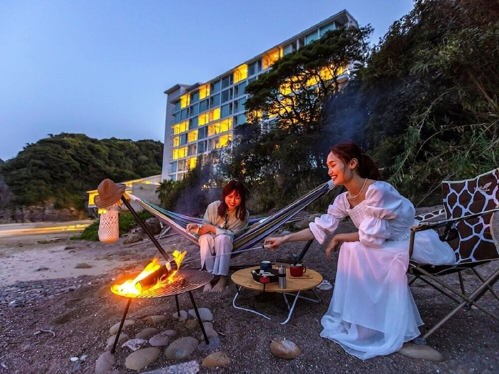 Beautiful young woman drinking tea near campfire