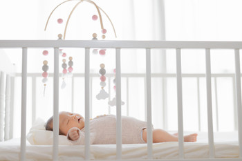 Baby sleeping under a mobile, one month old