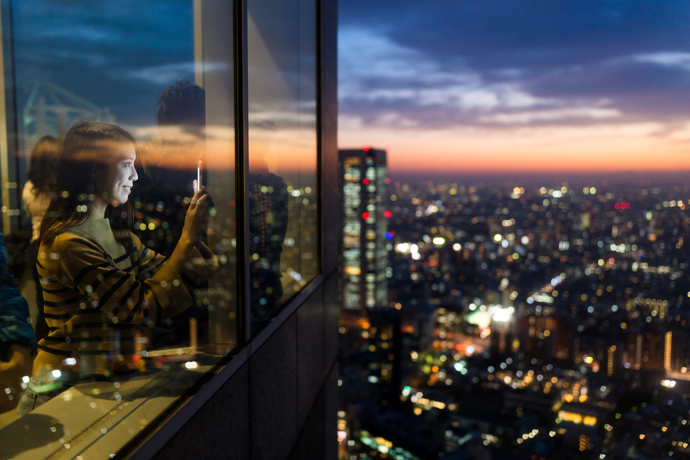 Woman visit the terrace and taking photo of the sunset in Tokyo city
