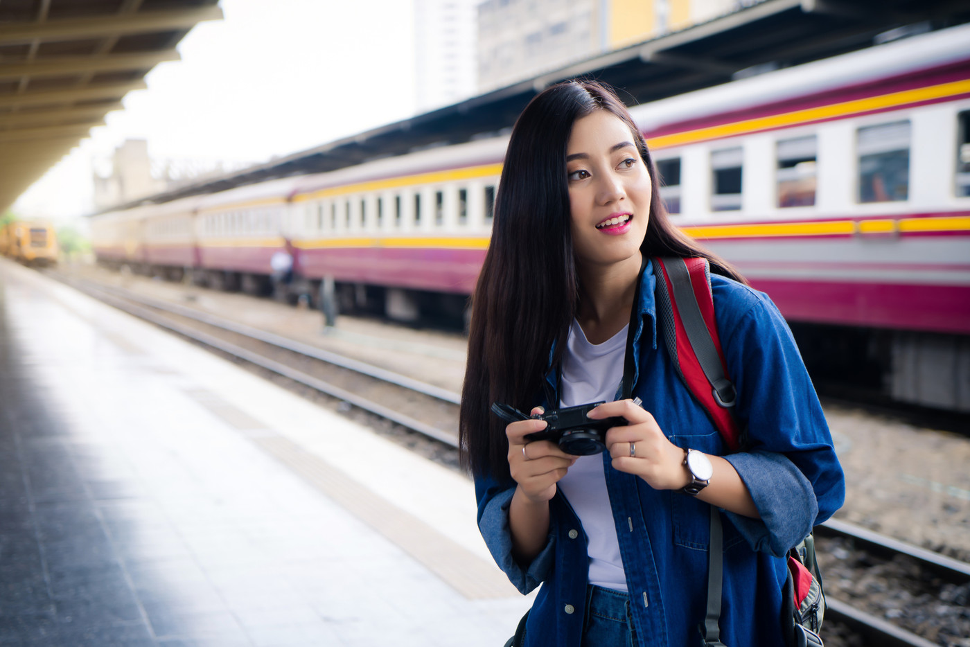 Young traveler woman holding camera train station.