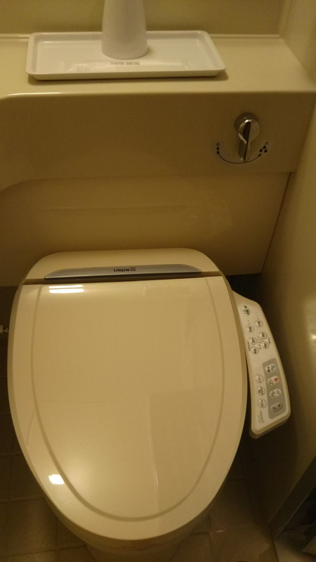 ウォシュレット付きトイレ、上にはコップと歯ブラシ。