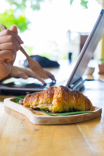 women using a fork to eat croissants