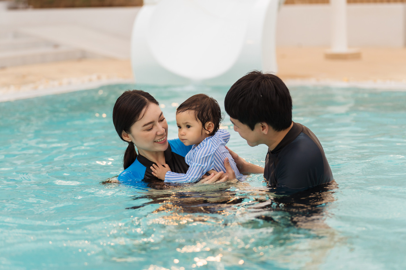 happy family. father and mother with small daughter in swimming pool.