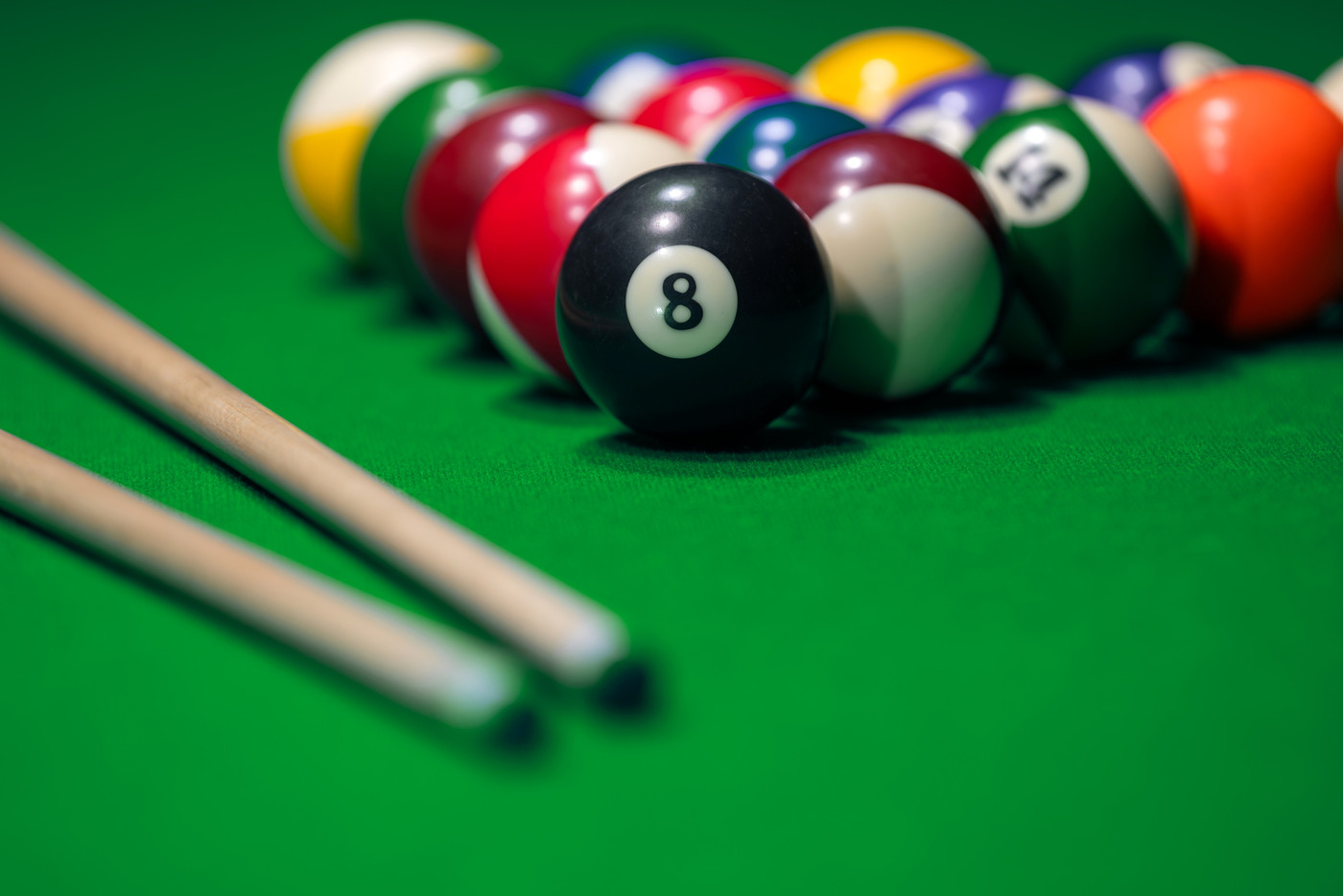 Many colorful billiard balls and cue on green table