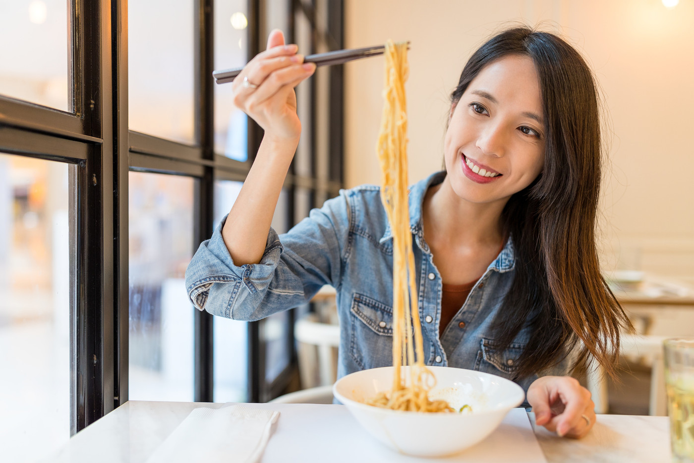 Asian Woman eating noodles in chinese restaurant