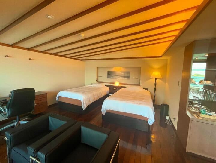 ベッドが置かれたフローリングや布団を敷ける畳とリビングスペースにはソファがあり、お部屋にはなんとマッサージチェアも! / 1