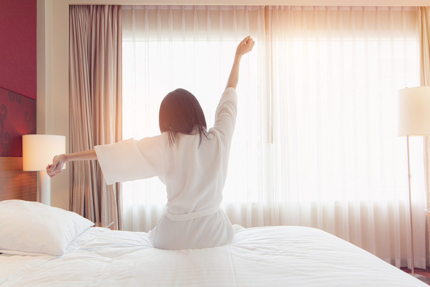 Woman stretching in bed after waking up, back