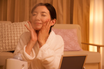 A middle-aged woman who uses a moisturizing facial device before going to bed