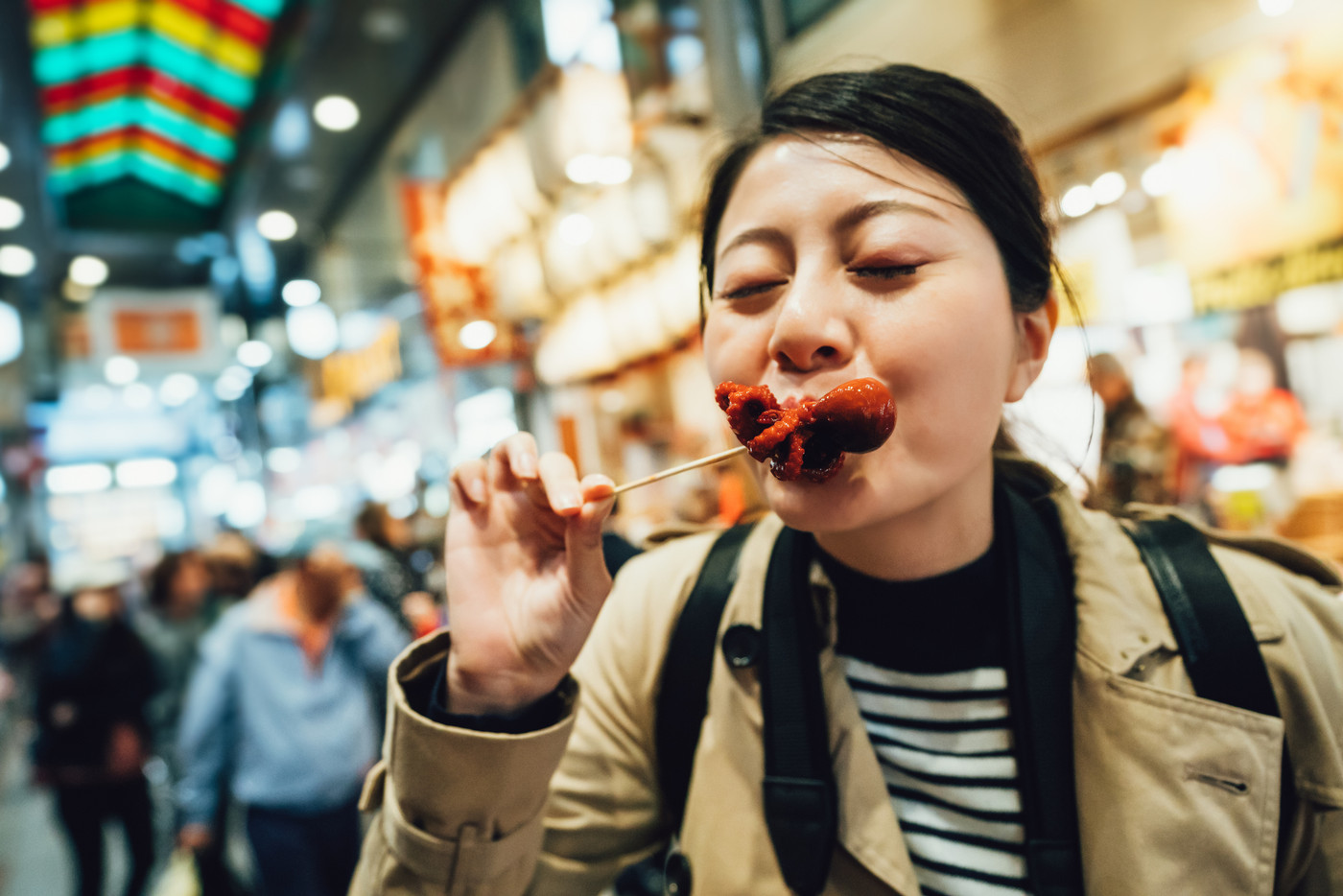 cheerful woman closing eyes trying street food