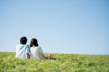 Rear view of a couple having a picnic on the meadow