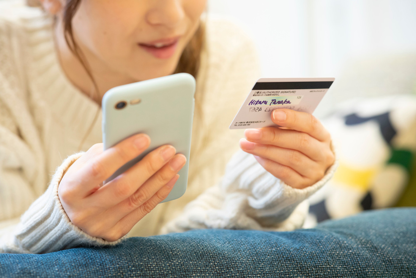 女性　ニット　寝転ぶ　スマホ　スマートフォン　携帯　携帯電話　カード　クレジットカード