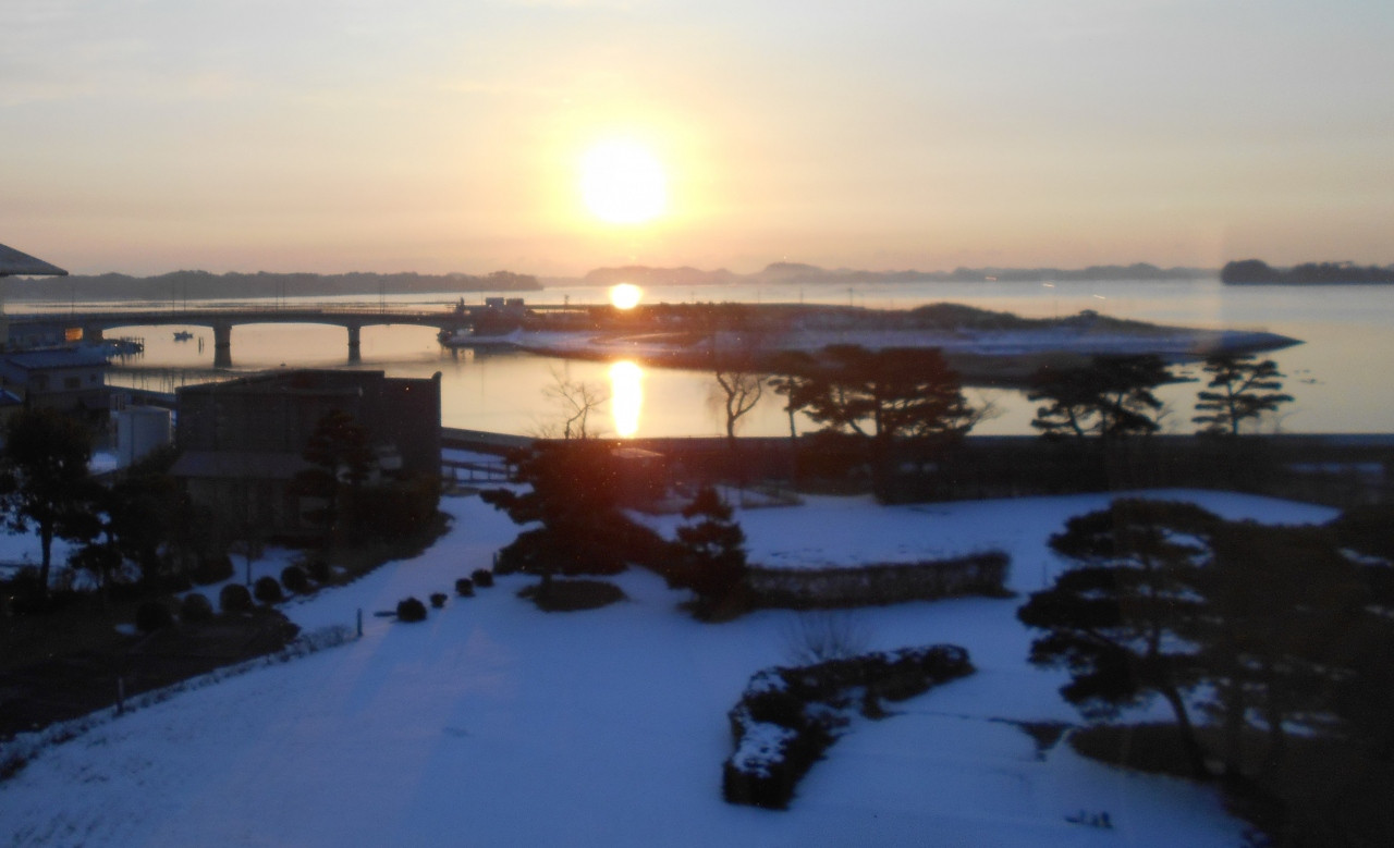 雪の庭園の先に松島湾の海。そこに日が昇りました。