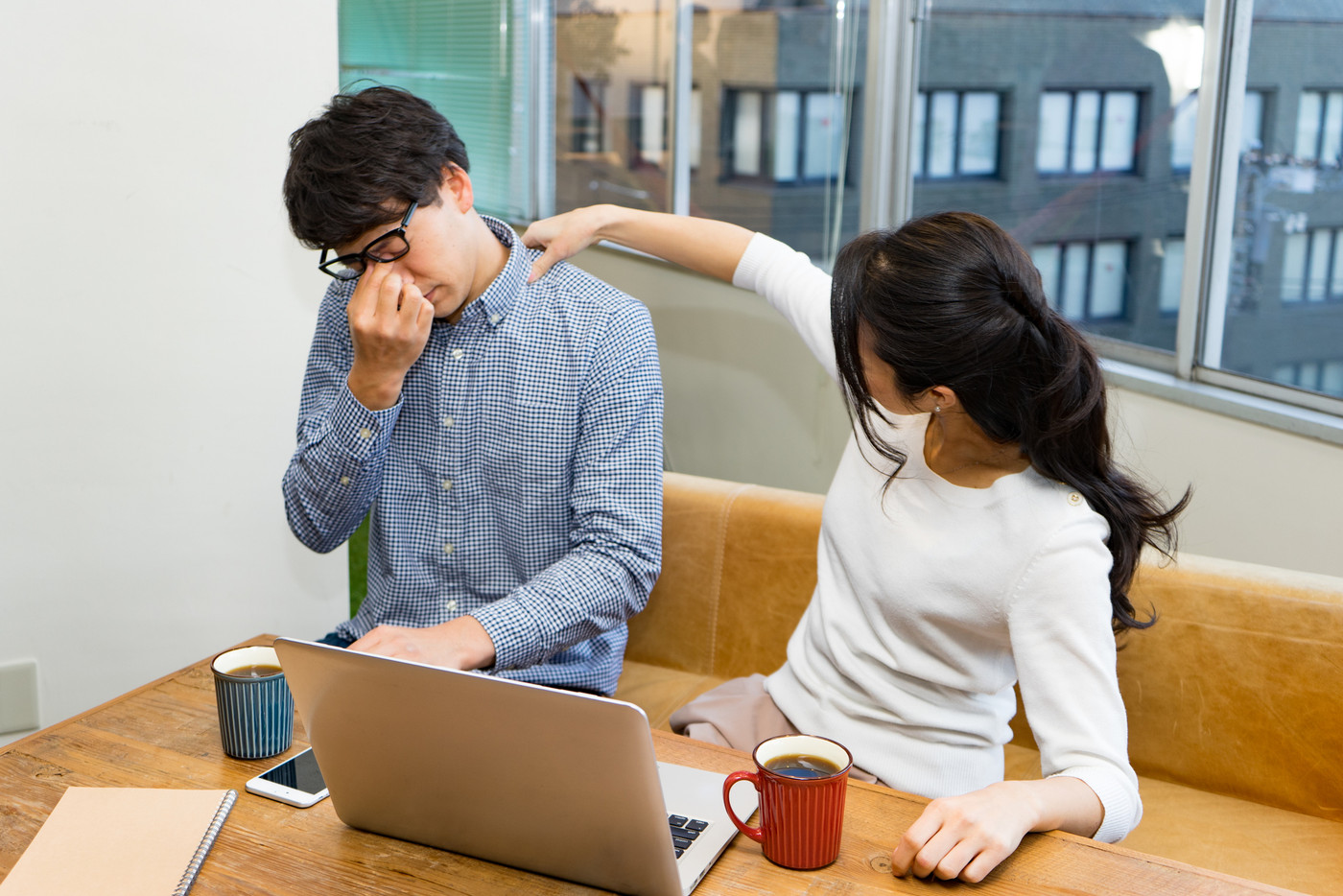 仕事の合間に肩こりをほぐす男女