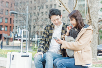 Couple looking at smartphone while traveling, smiling