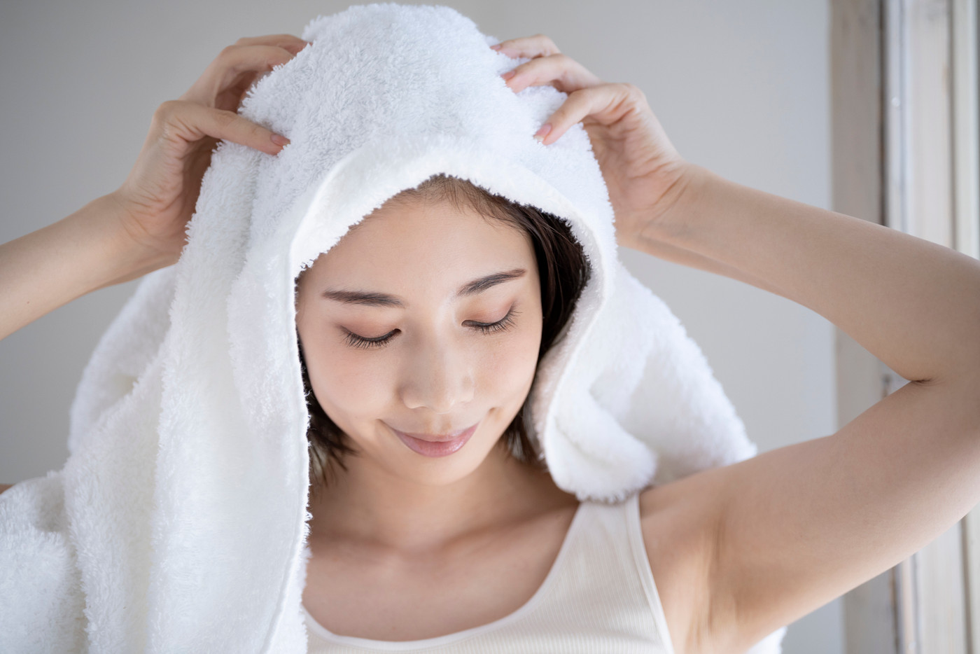 タオルで髪を拭く若い女性