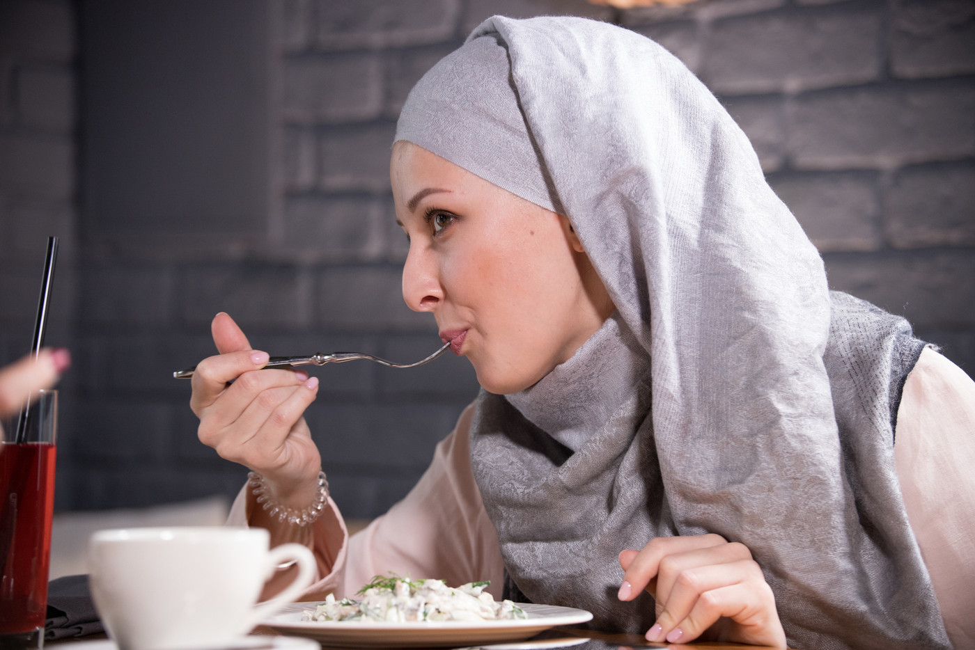 Young Muslim woman eats food in a cafe