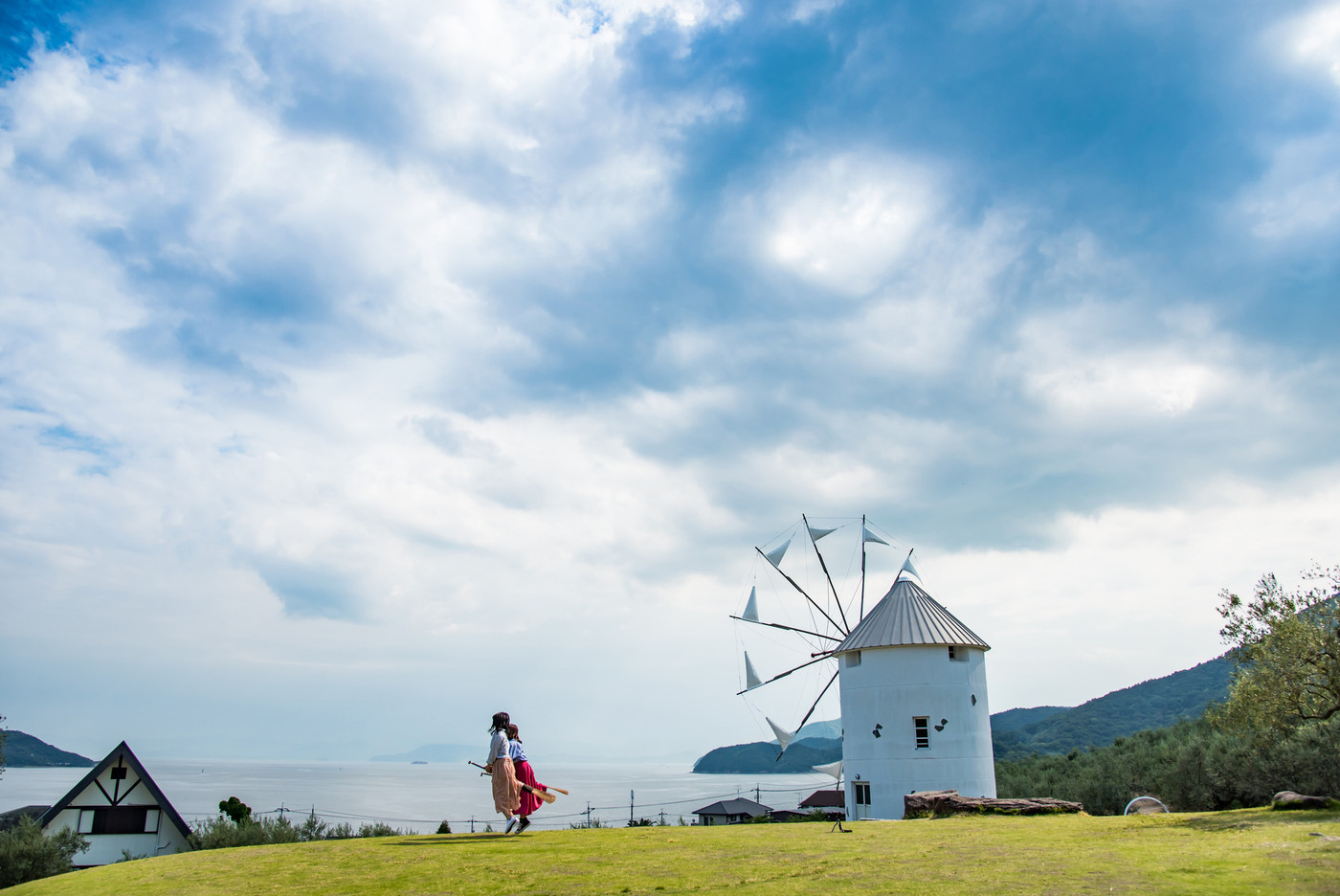 小豆島　道の駅　初夏のオリーブ公園　ギリシャ風車の前で魔法のほうきに乗る女性