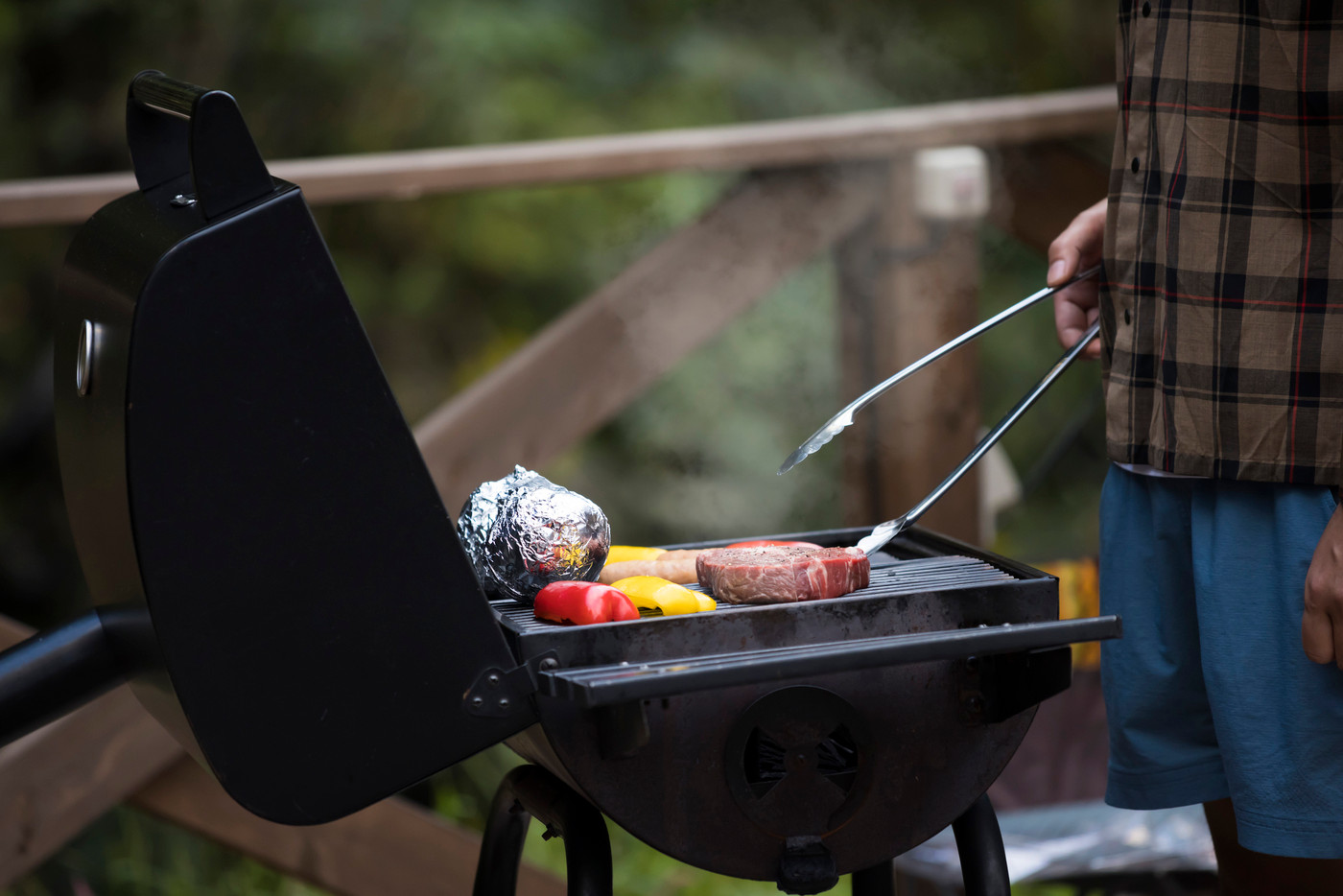 グランピング施設のバーベキューコンロで食材を焼く男性手元
