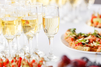 Bartender pouring champagne or wine into wine glasses on the table in restaurant.