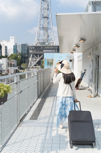 スーツケースを引いて名古屋観光をする若い女性 後ろ姿