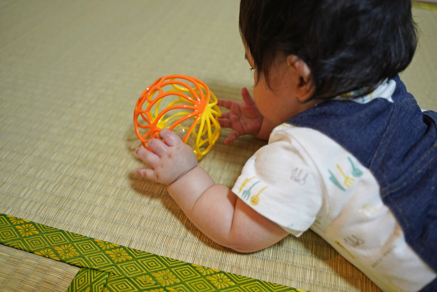 おもちゃで遊ぶ赤ちゃんの後ろ姿