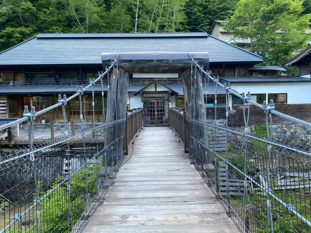 浴衣姿で宝川に架かる吊橋を渡り、手つかずの自然に囲まれた大露天風呂へ。敷地内の4本の源泉から毎分1800リットルもの湯が湧き、24時間新鮮な温泉を楽しめる / 1