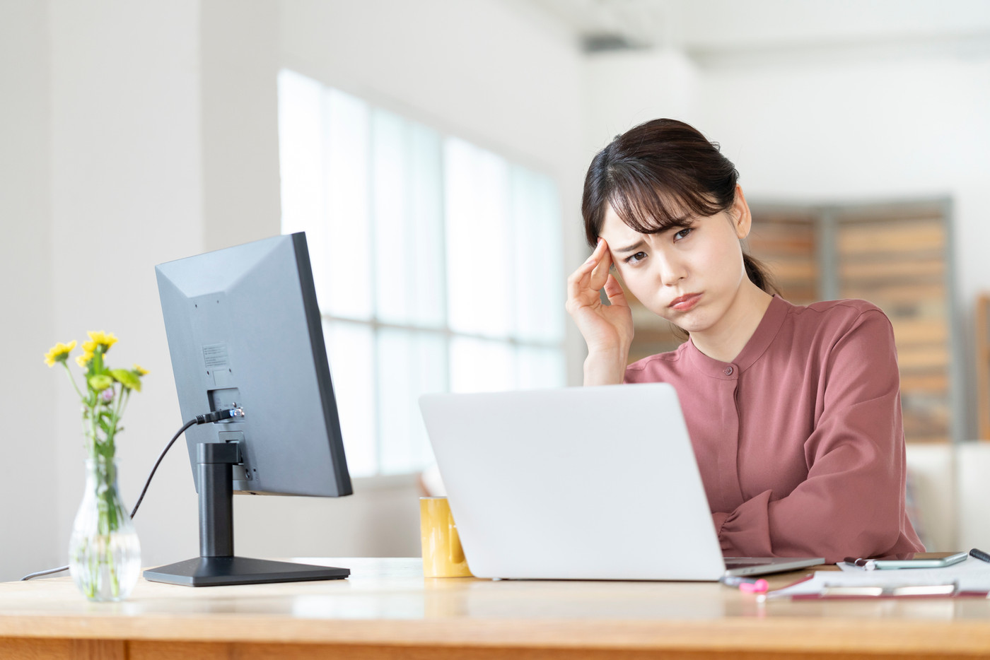 パソコンの前で頭を抱える若い女性