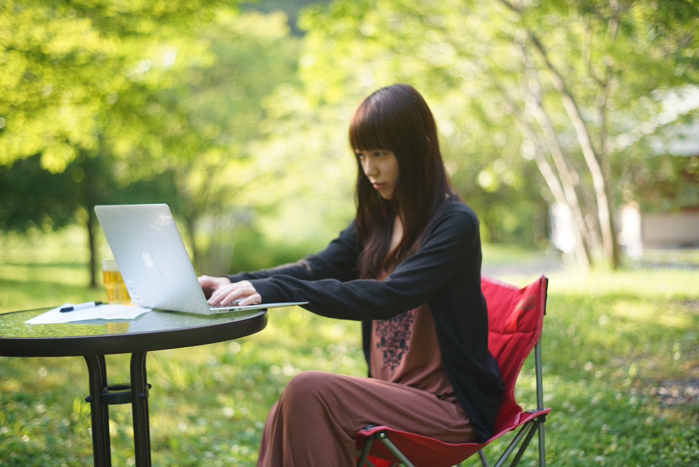 リモートワークで、自然の中でも働く女性の写真