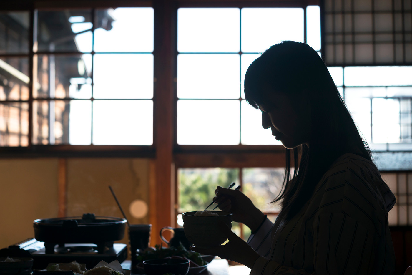 シルエット　旅館で日本料理を食べる若い女性