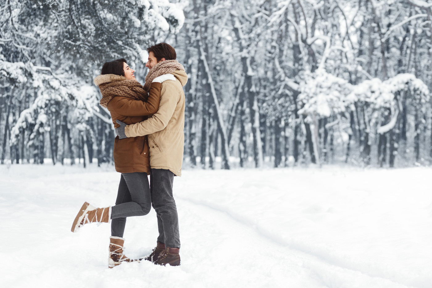 Couple Embracing Standing In Snowy Winter Forest In The Morning