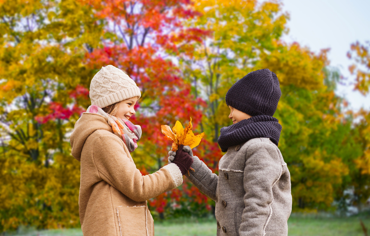 kids with autumn maple leaves over park background