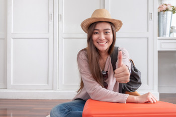 Young asian woman traveler thumbs up with orange