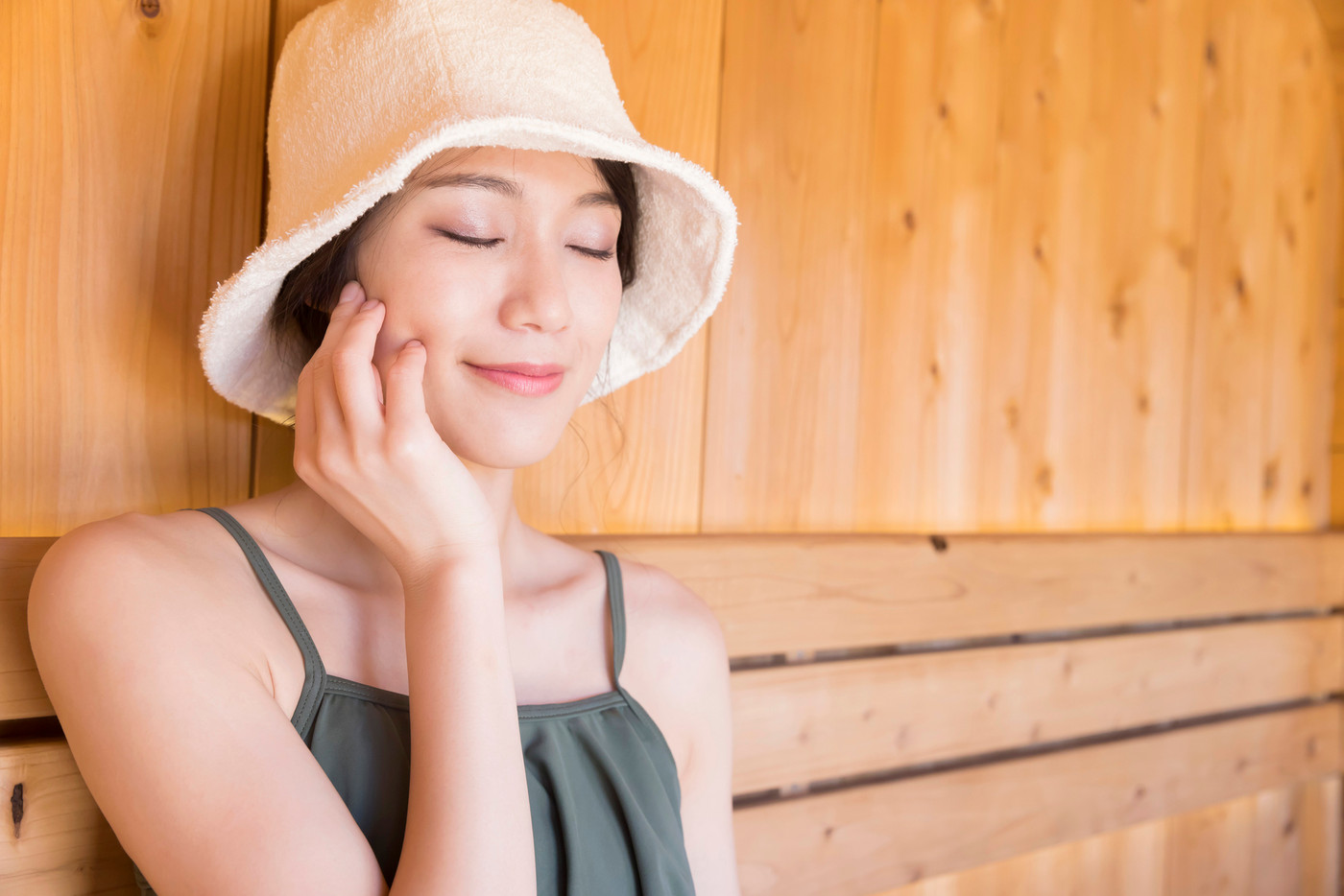 サウナハットをかぶってサウナに入る若い女性 ととのう