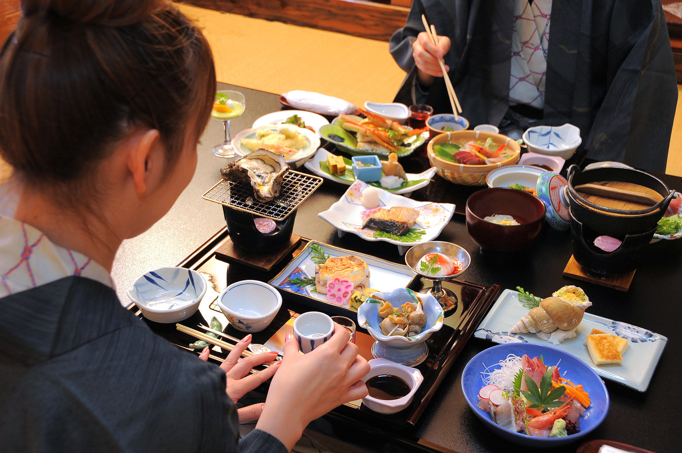 温泉宿の食事 浴衣でおちょこを持つ女性