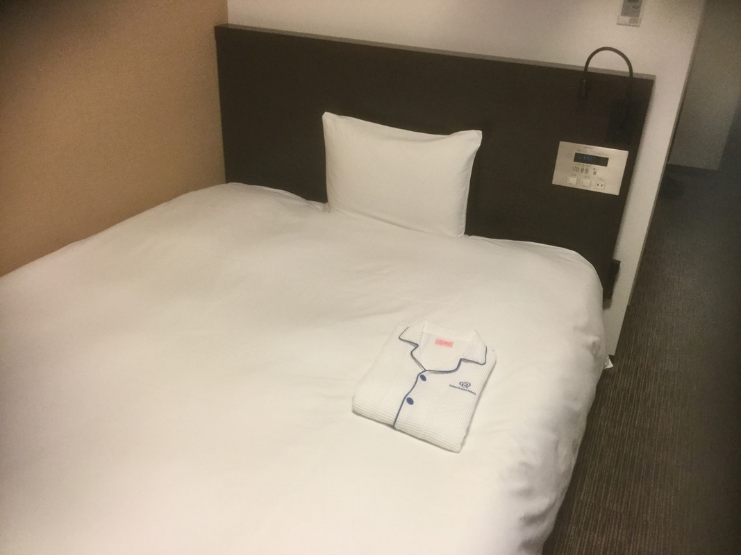 ベッド。枕元を照らす照明あり