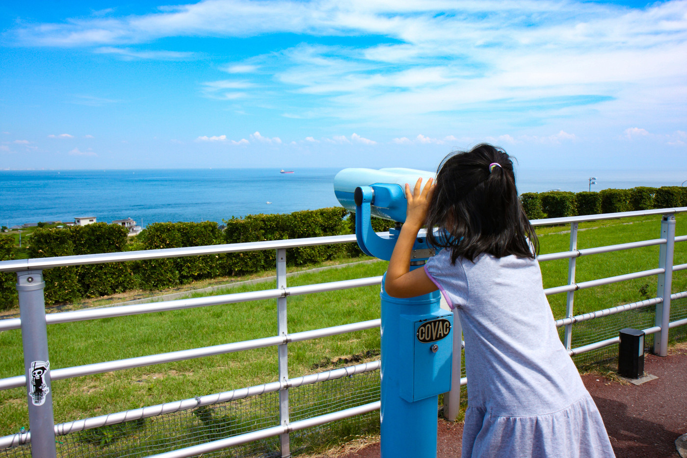 海と青空と望遠鏡を覗く女の子