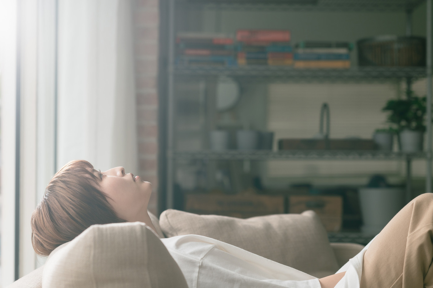 ソファーに座って天井を見ながら物思いにふける若い女性