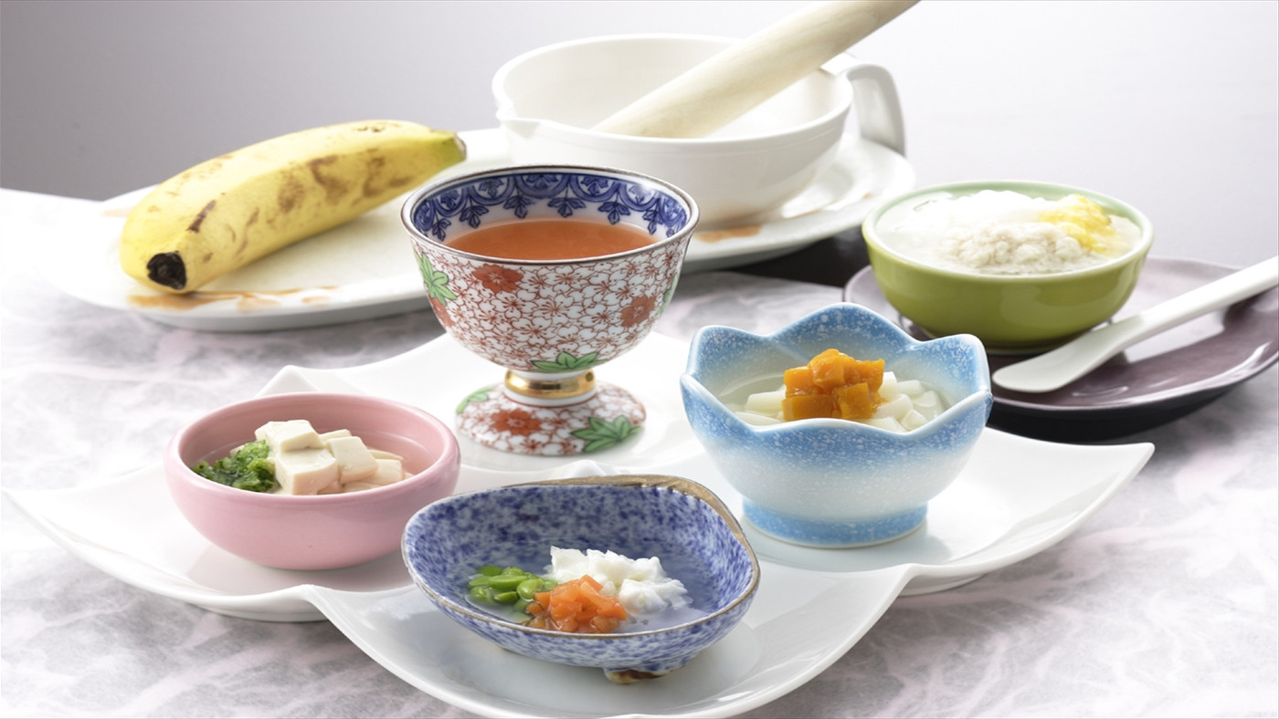 窓辺でベビーチェアに座って離乳食を食べる赤ちゃん