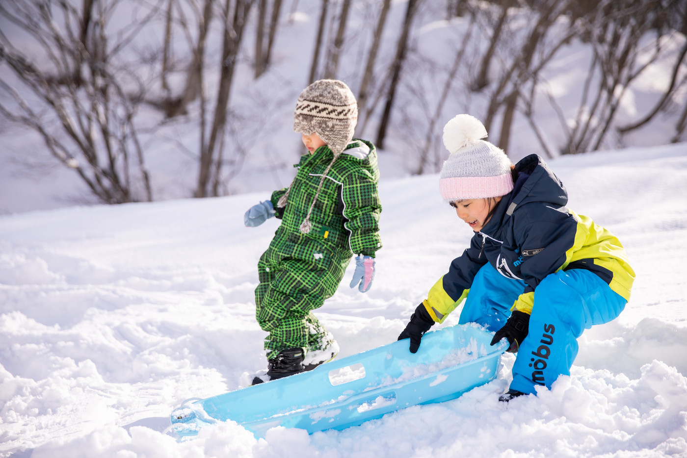 女の子と男の子の子供がスキー場で遊んでいる
