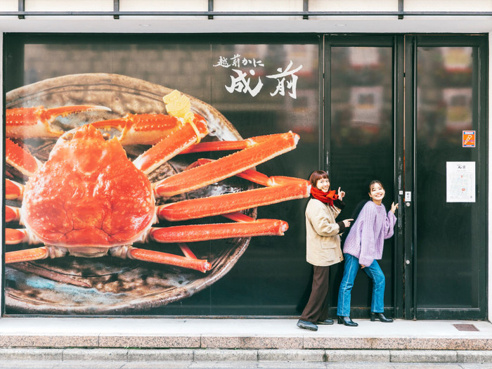 いけすの入り口にある大きなかにの前で記念撮影！ かにの品質に対する自信が表れているかのような、迫力の光景です