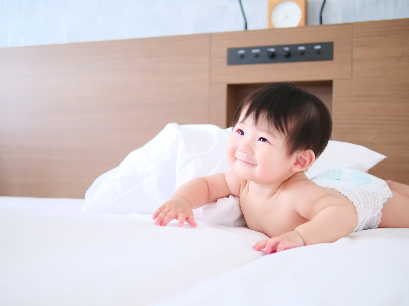 赤ちゃんがおむつ姿でベッドの上ではいはいしている