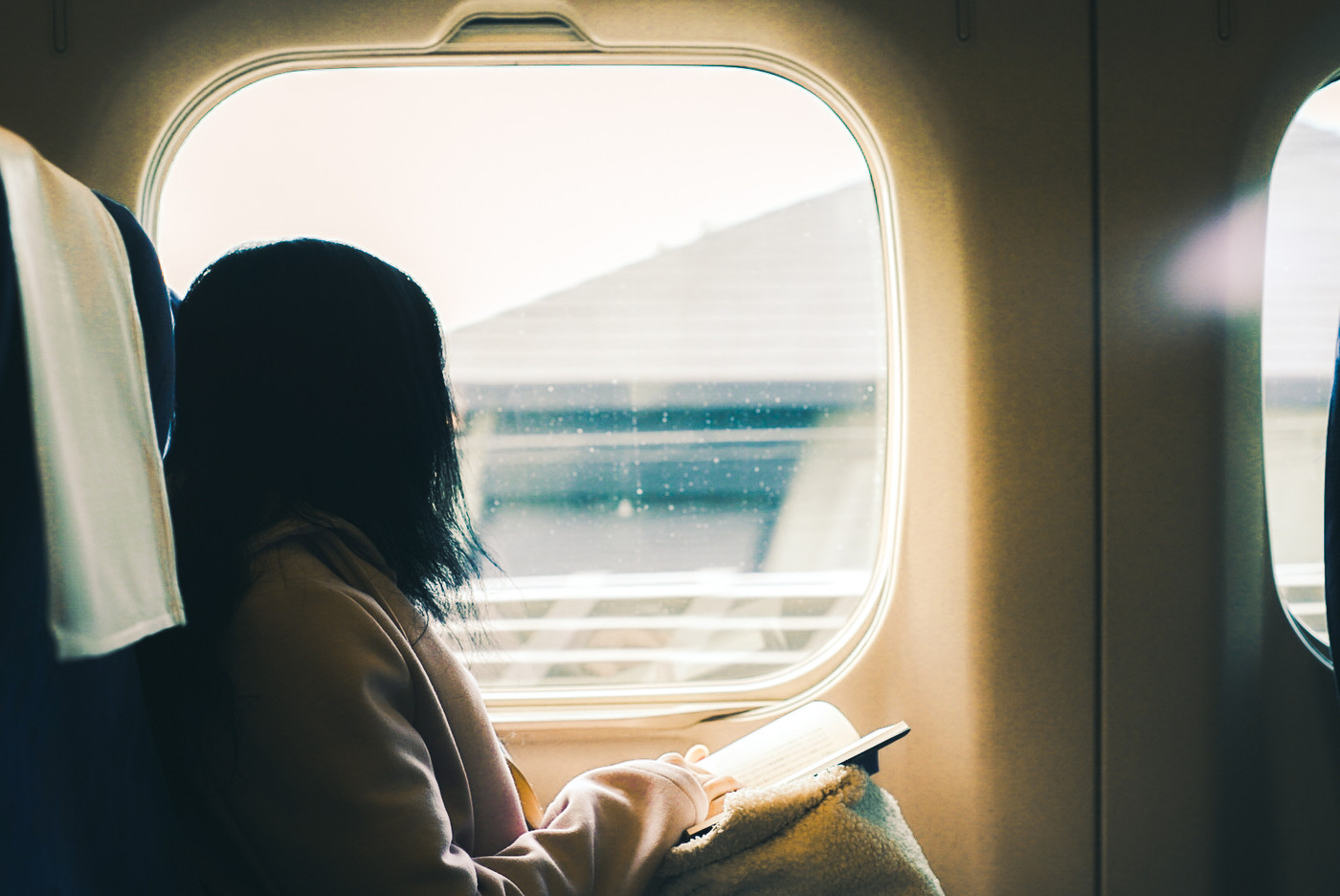 本を読みながら窓の外を眺める彼女