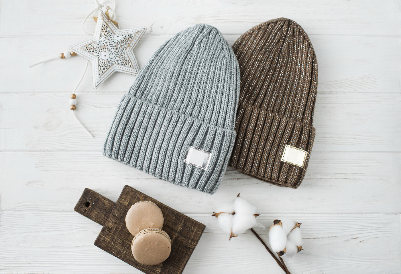 Knitted hats, cotton sprigs, macaroons close-up on a white