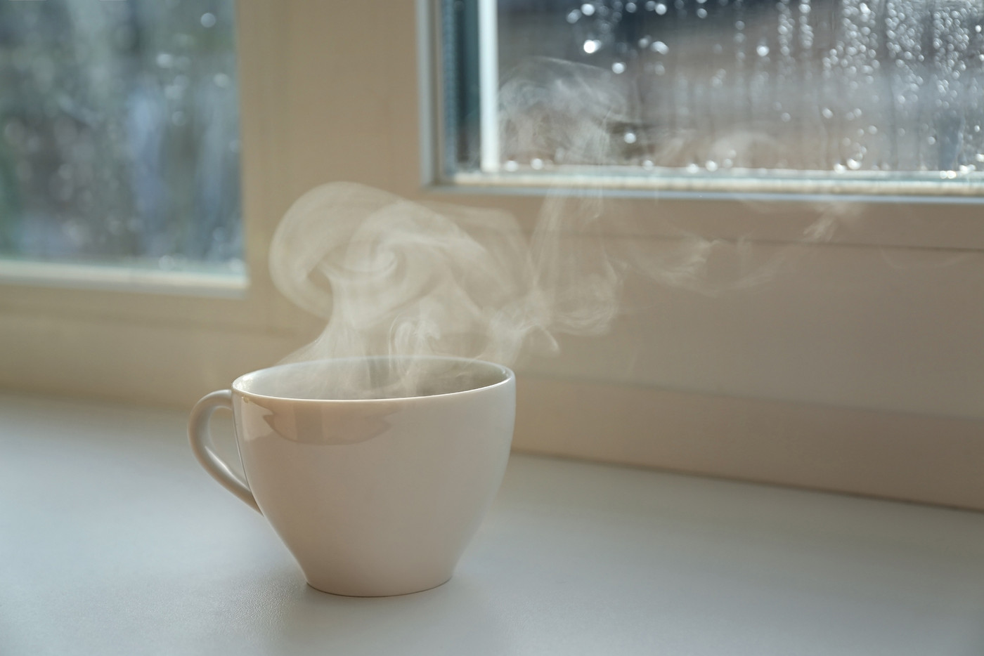 Cup of hot drink near window on rainy day.  Space for text