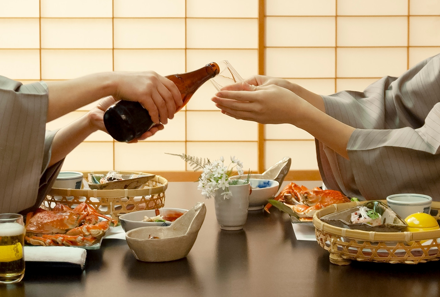 旅館でお酌をし合う浴衣姿の女性の手元