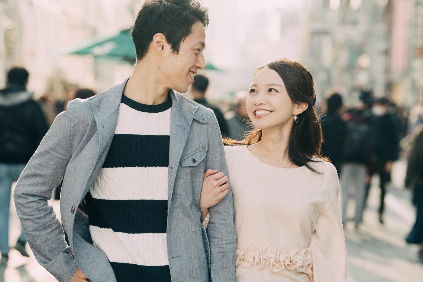 腕を組んで歩く若いカップル 笑顔