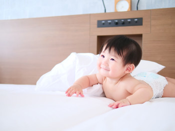 Baby in diapers crawling on the bed
