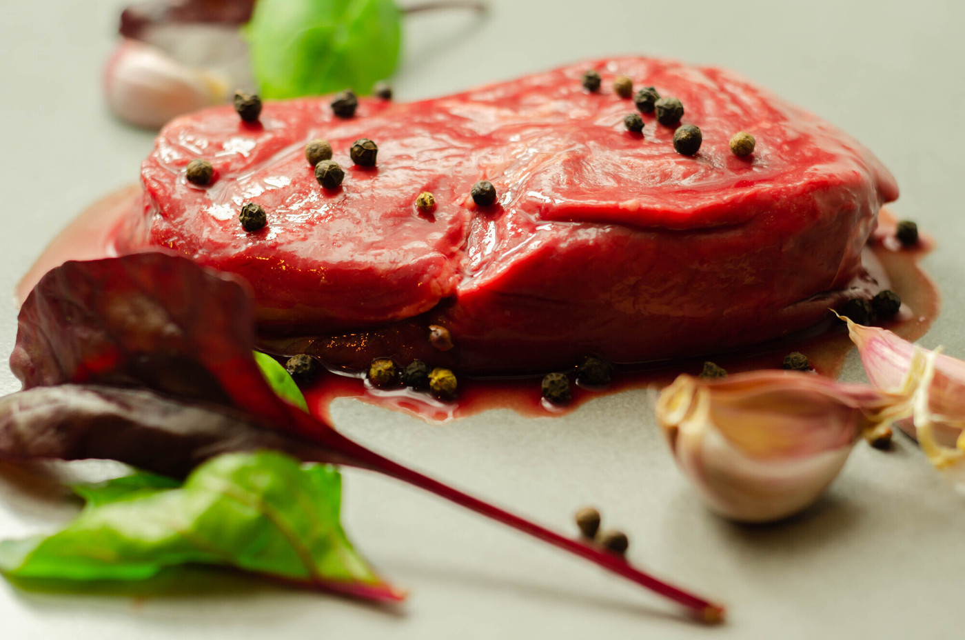 Raw beef sirloin steak with peppercorns and garlic prepared for frying
