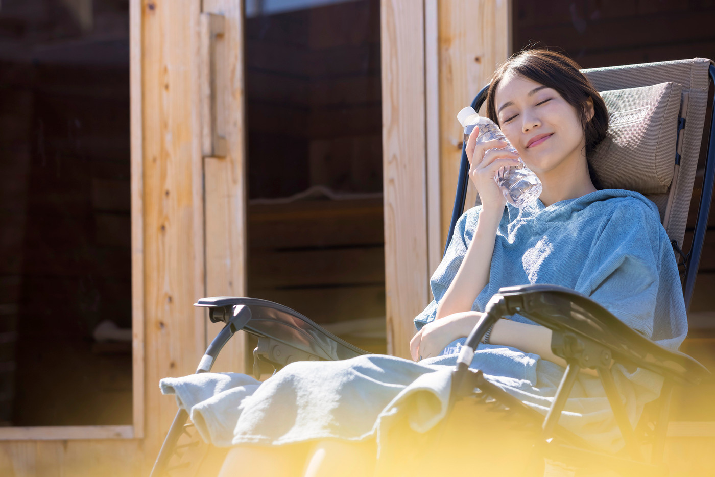 屋外サウナの前でサウナポンチョを着て外気浴をするサウナ女子
