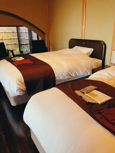 客室「暁」のベッドルーム。シモンズ社製ベッドや高級羽毛布団など、寝具にもこだわりが。ゆっくりと体の疲れを癒せそう。和室に布団を敷き、最大4人まで宿泊することもできる / 2